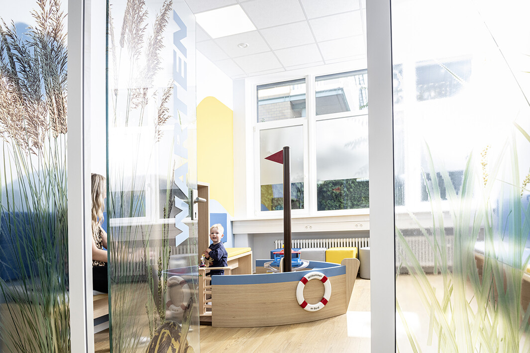 Wartezimmer mit kindgerechter Einrichtung für die Autismussprechstunde, mit bunten Möbeln und Wanddekoration.